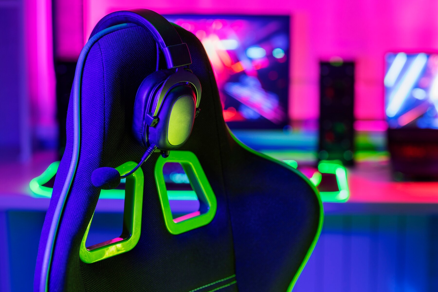 A gaming chair with vibrant green accents and a headset rests against a colorful LED-lit background, creating an immersive atmosphere.